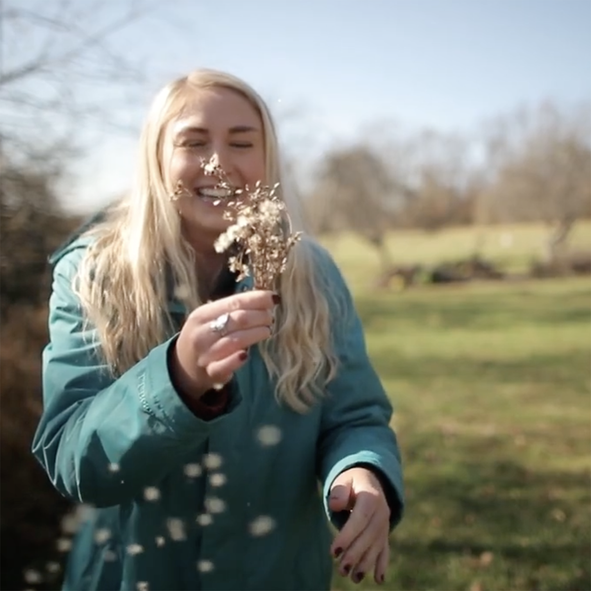 A student smiles and holds a flower at the Sensory Garden